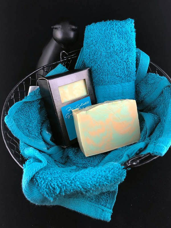 two bars of moon prism power scented soap sitting in a basket nested in a bundle of towls in a basket. A sassy smiling cat statue smirks up at the viewer